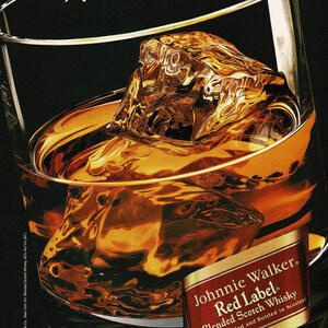 May include: A glass of amber-colored whisky with large ice cubes, reflecting light. The text "Enjoy the richness of Red" and "Richer in taste" are visible. A label for Johnnie Walker Red Label Blended Scotch Whisky is also present.