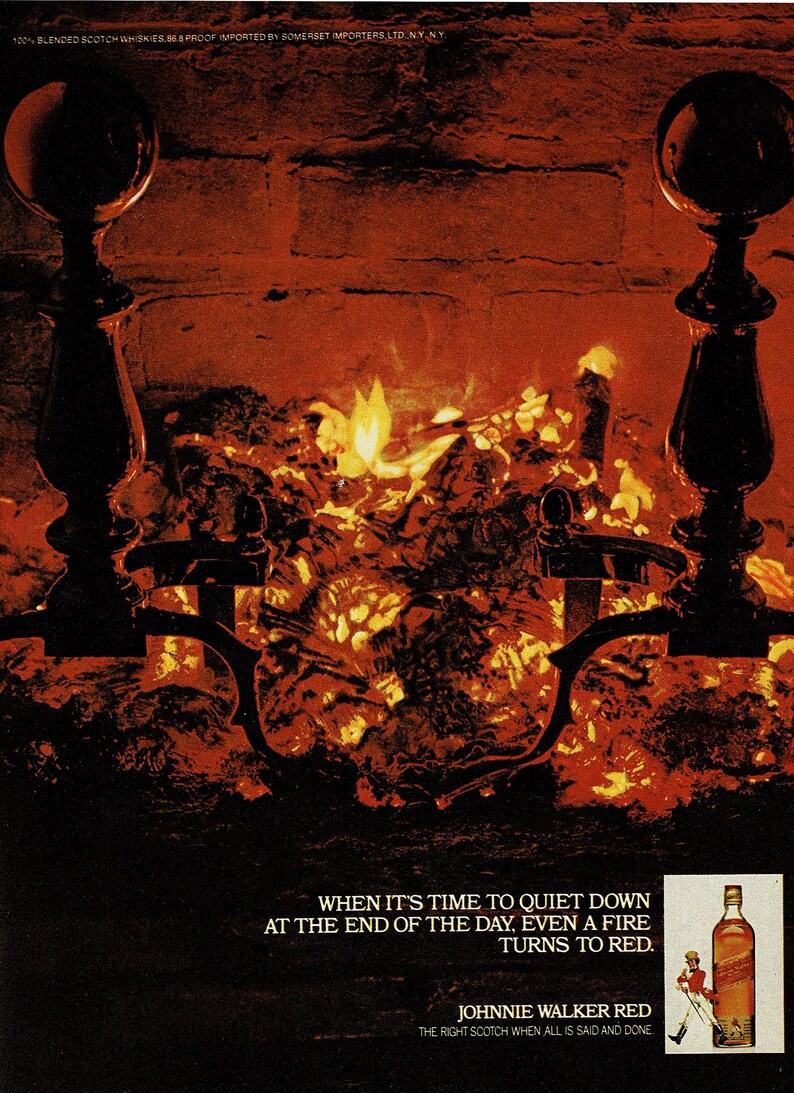 May include: An advertisement featuring a fireplace with a roaring fire, flanked by black iron and brass fire tools. The text reads "When it's time to quiet down at the end of the day, even a fire turns to red." A bottle of Johnnie Walker Red is shown.