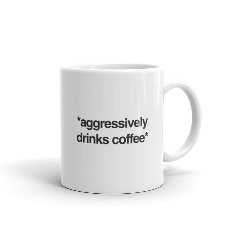 May include: White ceramic coffee mug with black text that reads "*aggressively drinks coffee*"