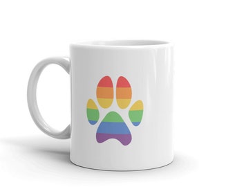 May include: White ceramic mug with a rainbow paw print design. The paw print is made up of the colors of the rainbow, red, orange, yellow, green, blue, indigo, and violet.