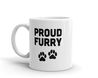 May include: White ceramic coffee mug with black text that reads "PROUD FURRY" and two black paw prints below the text.