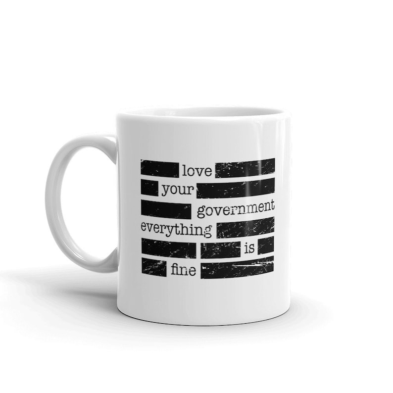 May include: White ceramic mug with black text that reads "love your government everything is fine".