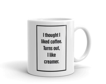 Puede incluir: Taza de café de cerámica blanca con un borde negro alrededor del texto "Pensé que me gustaba el café. Resulta que me gusta la crema."