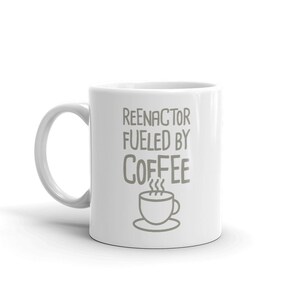 May include: White ceramic coffee mug with the text "Reenactor Fueled by Coffee" and a cartoon image of a steaming cup of coffee.