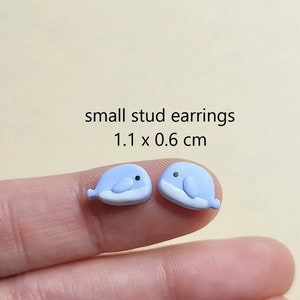 May include: A pair of small blue whale stud earrings. The earrings are 1.1 x 0.6 cm.