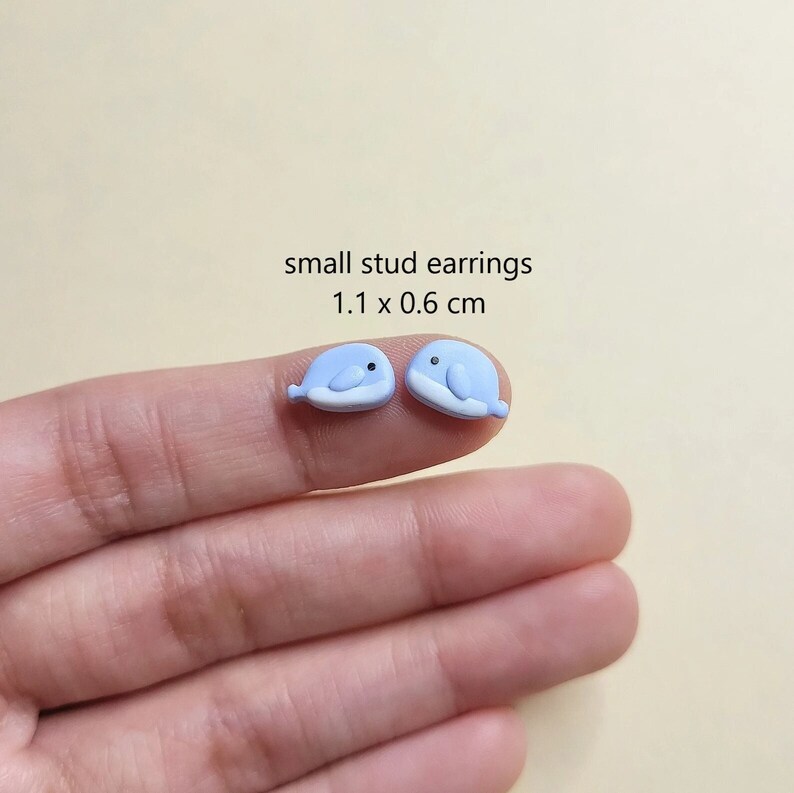 May include: A pair of small blue whale stud earrings. The earrings are 1.1 x 0.6 cm.