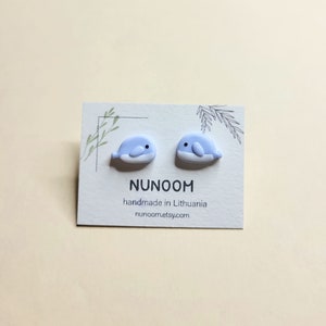 May include: A pair of light blue whale stud earrings on a white card with the text "NUNOOM handmade in Lithuania nunoom.etsy.com"
