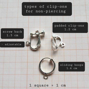 May include: Close-up of three different types of clip-on earrings for non-piercing ears. The earrings are silver-toned and measure 1.2 cm, 1.4 cm, and 1.5 cm in diameter. The text "screw back 1.5 cm adjustable" is written on a white background. The text "padded clip-ons 1.2 cm" is written on a white background. The text "sliding hoops 1.4 cm" is written on a white background. The text "1 square = 1 cm" is written on a white background.