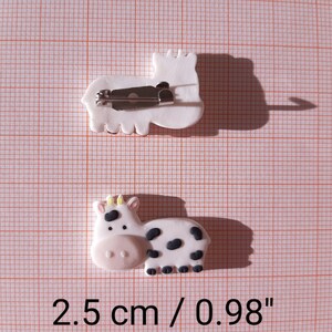 Pu&ograve; includere: Due spille in argilla bianca con un fermaglio argentato. Una spilla &egrave; una mucca con macchie nere e l'altra &egrave; un cavallo. Le spille misurano 2,5 cm o 0,98 pollici.