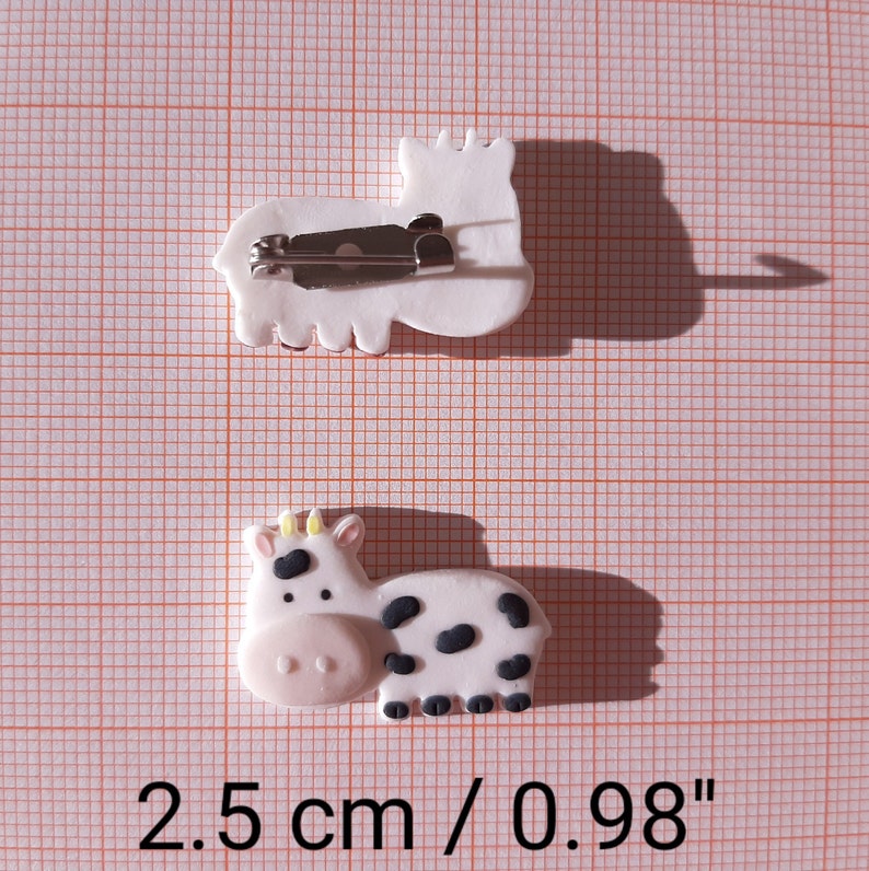 Pu&ograve; includere: Due spille in argilla bianca con un fermaglio argentato. Una spilla &egrave; una mucca con macchie nere e l'altra &egrave; un cavallo. Le spille misurano 2,5 cm o 0,98 pollici.