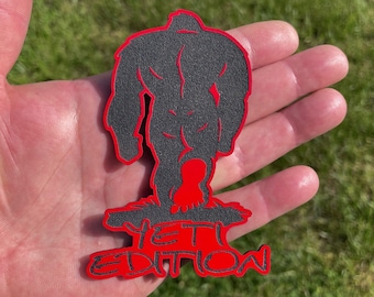 May include: Black silhouette of a Yeti with red outline, standing on a red base with the text "YETI EDITION" in black.