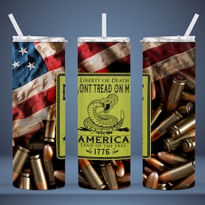 May include: A stainless steel tumbler with a design featuring an American flag, a snake with the text "Liberty or Death Don't Tread on Me", and bullets. The text "America Land of the Free 1776" is also included.