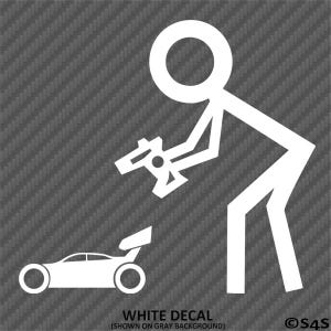 Pode incluir: Autocolante branco com uma figura de palito segurando um controle remoto, olhando para um carro de corrida branco com um aerofólio. O texto "WHITE DECAL" está na parte inferior, com "(SHOWN ON GRAY BACKGROUND)" abaixo.