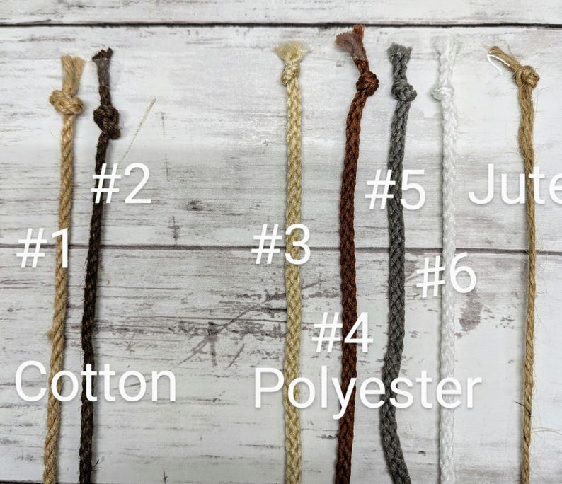 May include: An overhead shot displays six different cords against a light wood background. The cords are labeled with numbers and material types: cotton, polyester, and jute. The cords vary in color from light tan to dark brown and gray.