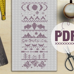 Może przedstawiać: Wzór do haftu krzyżykowego z fioletowym wzorem przedstawiającym scenę górską, fazy księżyca i tekst "Go Outside". Wzór jest na białym płótnie Aida i jest dołączony do etykiety PDF.