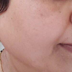 Puede incluir: Una mujer con pendientes de aro de oro con peque&ntilde;as piedras transparentes y un aro de nariz de oro con piedras transparentes.
