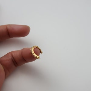 Puede incluir: Un aro para la oreja de color dorado con una fila de peque&ntilde;os diamantes de imitaci&oacute;n transparentes alrededor del borde.