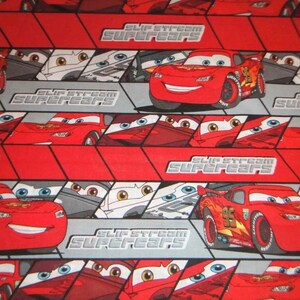 Puede incluir: Tela roja y gris con un patr&oacute;n repetido de un coche de carreras rojo con el n&uacute;mero 95 en el lateral. El texto "Slip Stream Supercars" se repite en toda la tela.