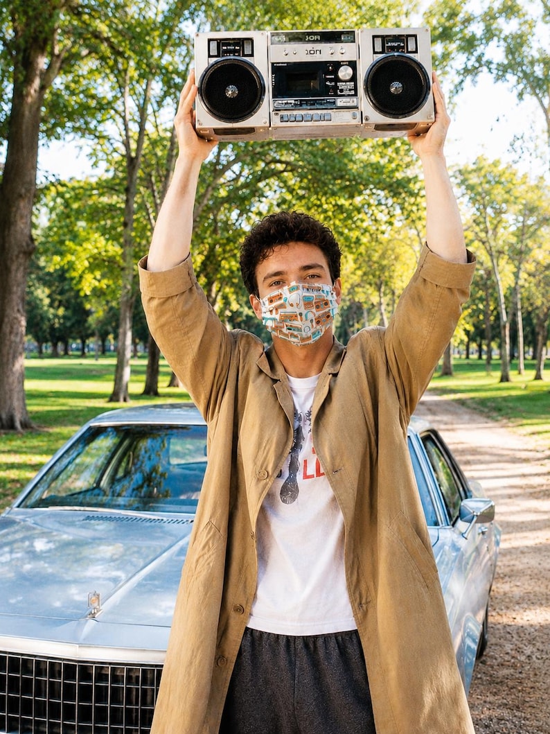 May include: A silver portable cassette player with two large speakers held overhead. The device features a central cassette deck, various control knobs, and a handle. It is a classic boombox design with a metallic finish and black speaker grilles.