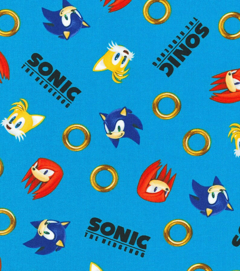 Op de afbeelding: Een blauwe achtergrond met herhalende afbeeldingen van Sonic the Hedgehog-personages, waaronder Sonic, Tails, Knuckles en gouden ringen. De tekst "Sonic The Hedgehog" wordt herhaald in het hele patroon.