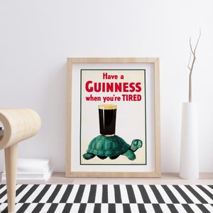 Op de afbeelding: Een vintage Guinness-reclame met een groene schildpad die een glas Guinness draagt met de tekst "Have a GUINNESS when you're TIRED".