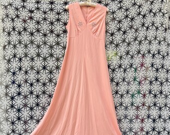 May include: A sleeveless, peach-colored maxi dress with a V-neckline and a beaded design on the bodice.