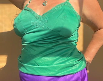 May include: A green satin camisole with lace trim and a bow detail. The camisole is worn over a purple satin skirt.