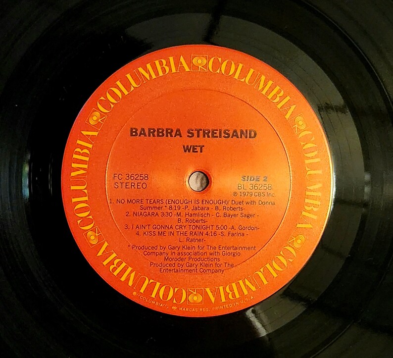 May include: A vintage vinyl record by Barbra Streisand, titled "WET." The orange and black record features the Columbia Records logo and song titles, including "No More Tears" and "Kiss Me in the Rain." The record is a stereo recording.