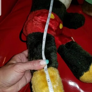 K&ouml;nnte beinhalten: Ein schwarzes und rotes Pl&uuml;sch-Mickey-Mouse-Spielzeug mit gelben Schuhen. Das Spielzeug ist 48 cm gro&szlig; und wird mit einem Ma&szlig;band gemessen.