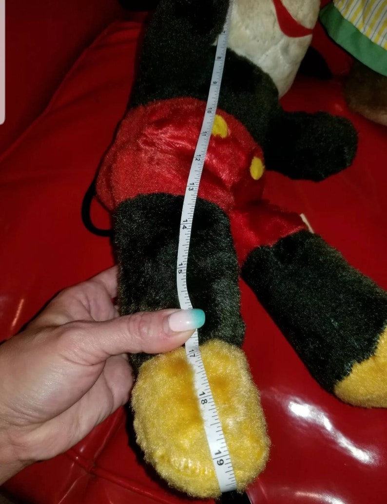 K&ouml;nnte beinhalten: Ein schwarzes und rotes Pl&uuml;sch-Mickey-Mouse-Spielzeug mit gelben Schuhen. Das Spielzeug ist 48 cm gro&szlig; und wird mit einem Ma&szlig;band gemessen.