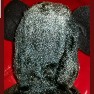 K&ouml;nnte beinhalten: Schwarzes Pl&uuml;schtier mit gro&szlig;en Ohren. Das Spielzeug ist aus weichem, flauschigem Material.