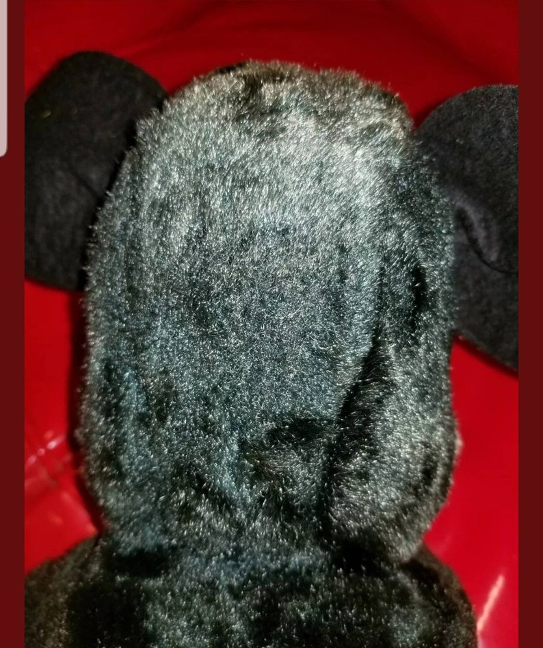 K&ouml;nnte beinhalten: Schwarzes Pl&uuml;schtier mit gro&szlig;en Ohren. Das Spielzeug ist aus weichem, flauschigem Material.