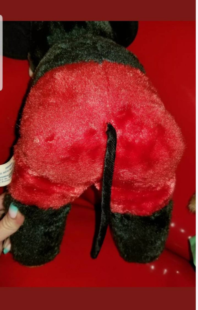 K&ouml;nnte beinhalten: Ein Pl&uuml;schtier von Mickey Mouse, das eine rote Hose mit einem schwarzen Schwanz tr&auml;gt. Das Spielzeug ist aus weichem, flauschigem Stoff und hat eine schwarze Nase und Augen.