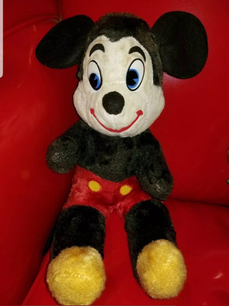 K&ouml;nnte beinhalten: Ein Vintage-Pl&uuml;schtier Mickey Mouse mit schwarzem Fell, roten Shorts mit gelben Kn&ouml;pfen und gelben Schuhen. Das Spielzeug hat ein wei&szlig;es Gesicht mit schwarzen Augen und einer schwarzen Nase.