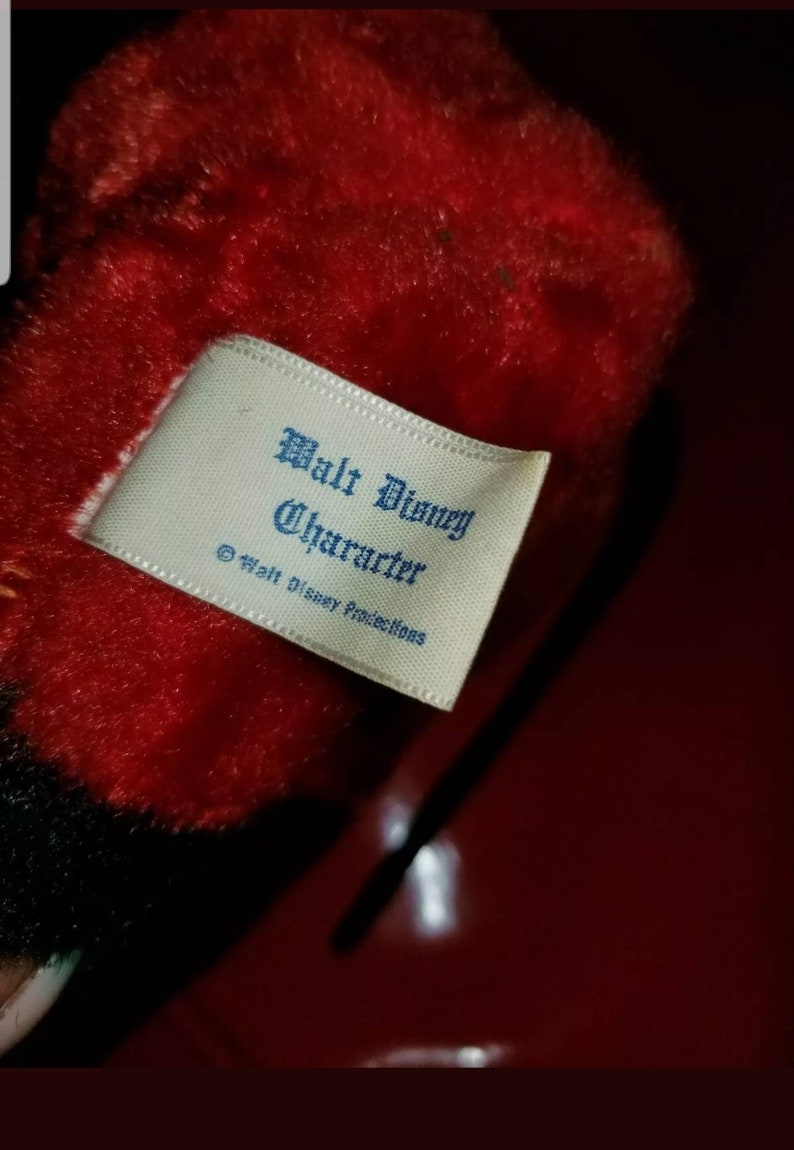 K&ouml;nnte beinhalten: Ein wei&szlig;es Etikett mit blauem Text, auf dem "Walt Disney Character &copy; Walt Disney Productions" steht.