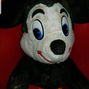 K&ouml;nnte beinhalten: Ein Vintage-Pl&uuml;schtier Mickey Mouse mit schwarzem Fell, wei&szlig;em Gesicht und roten Shorts mit gelben Kn&ouml;pfen. Das Spielzeug hat gro&szlig;e blaue Augen und eine schwarze Nase.