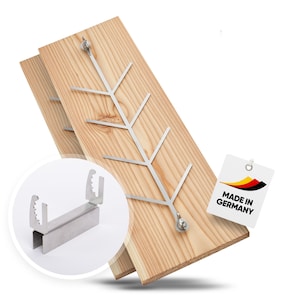 May include: A wooden plank with a metal tree-shaped design for grilling food. The plank is made in Germany. A close-up of a metal clamp is also shown.