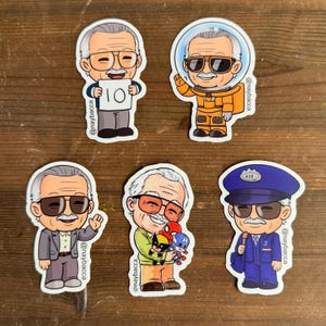 May include: A collection of colorful stickers featuring cartoon illustrations of a man with glasses and a mustache in various outfits. One sticker shows the man holding a sign with the number 10. The stickers have the text "@naybacca".