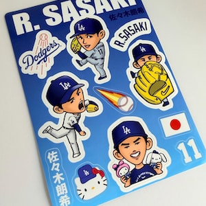 May include: A blue sticker sheet featuring R. Sasaki with the text R. SASAKI and 佐々木朗希. Includes cartoon illustrations of a baseball player in a Dodgers uniform, a flaming baseball, a Hello Kitty head with a Dodgers cap, and the Japanese flag.