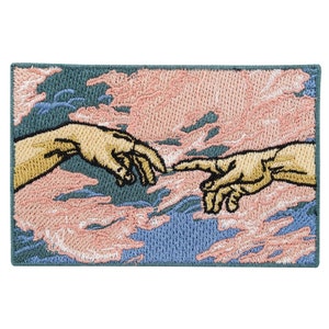 Könnte beinhalten: Gestickter Patch mit einer Nachbildung von Michelangelos Schöpfung Adams, die zwei Hände zeigt, die sich vor einem Hintergrund aus rosa und blauen Wolken aneinander reichen.