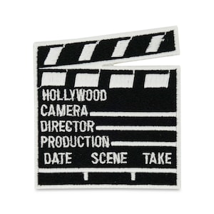 May include: Black and white embroidered patch of a clapperboard with the words "HOLLYWOOD", "CAMERA", "DIRECTOR", "PRODUCTION", "DATE", "SCENE", and "TAKE" written on it.