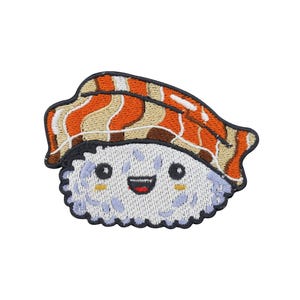 Puede incluir: Parche bordado con un personaje de sushi sonriente. El sushi tiene una base de arroz blanco con detalles azules, una cara feliz y un topping naranja, beige y marrón. El parche tiene un borde negro.