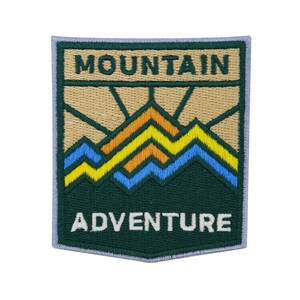 Può includere: Toppa ricamata verde con una scena di montagna beige e le parole "MOUNTAIN ADVENTURE" in bianco.
