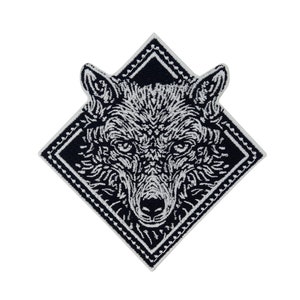 May include: Black and white embroidered patch of a wolf's face in a diamond-shaped frame.