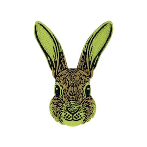 Op de afbeelding: Gestikt patch van een konijnenkop met bruine vacht, zwarte ogen en groene oren.