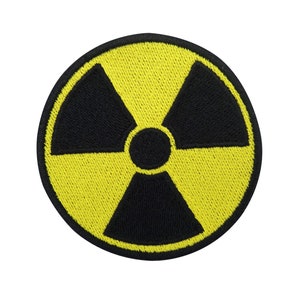Könnte beinhalten: Ein gestickter gelber und schwarzer Aufnäher mit einem Strahlungssymbol.