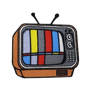 Puede incluir: Un parche bordado de un televisor vintage con una pantalla estática. El televisor es marrón con una pantalla negra y un borde blanco. La pantalla estática es un patrón colorido de rojo, amarillo, azul y gris.