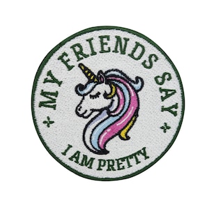 Op de afbeelding: Een witte geborduurde patch met een groene rand. De patch heeft een cartoon-einhorn met een roze en blauwe manen en staart. De tekst op de patch luidt "Mijn vrienden zeggen dat ik mooi ben".