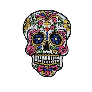 Könnte beinhalten: Gestickter Zucker Schädel Patch mit bunten floralen Details, blauen Augen und weißem Hintergrund.