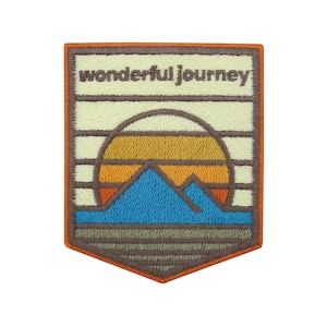 Könnte beinhalten: Ein gestickter Aufnäher mit einer Sonnenuntergangsszene und Bergen. Der Aufnäher ist beige mit orangefarbener, gelber, blauer und brauner Stickerei. Der Text "wonderful journey" ist oben auf dem Aufnäher in Braun gestickt.